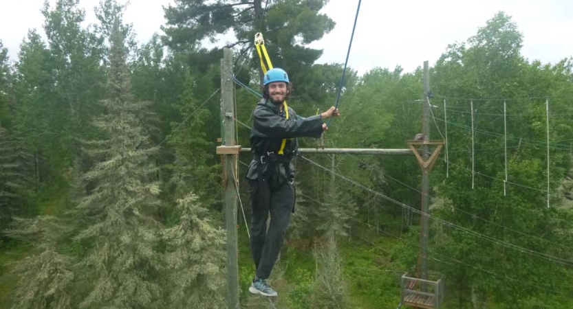 a student smiles while participating in a ropes course with outward bound